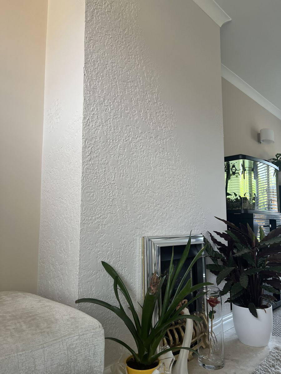 White textured plaster chimney breast with raised mandala relief